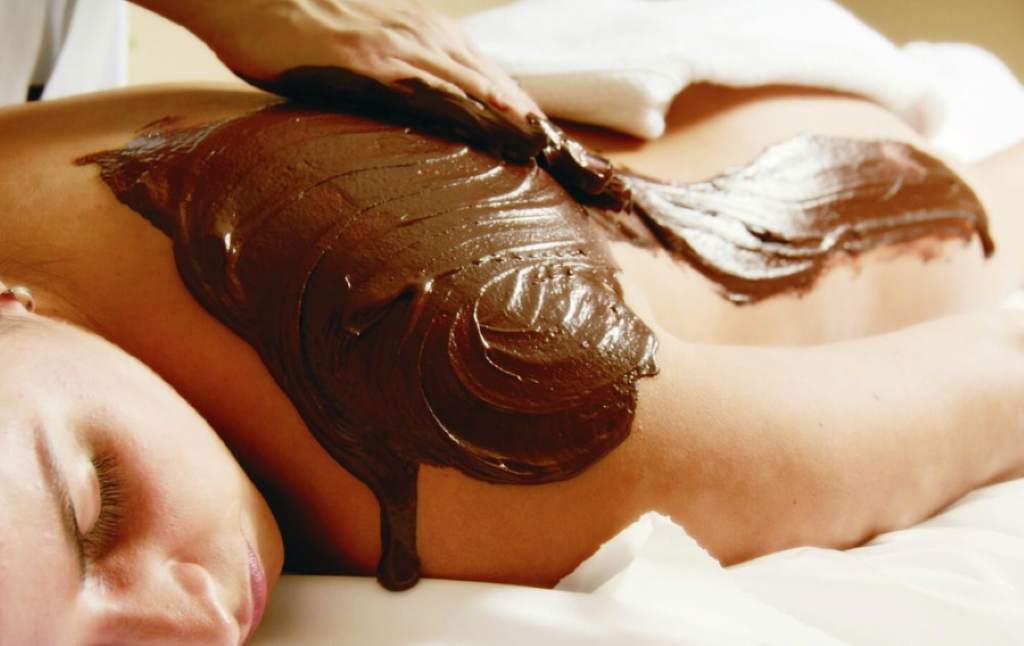 Woman relaxing in Chocolate Fondue Wrap with thermal blanket and soothing music at luxury hotel spa